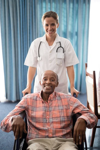 Médico de pie con hombre mayor discapacitado — Foto de Stock