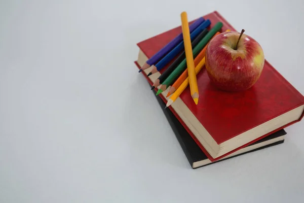 Manzana y lápices de color en libro —  Fotos de Stock