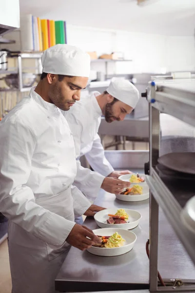 Dois chefs que guardam comida na cozinha comercial — Fotografia de Stock