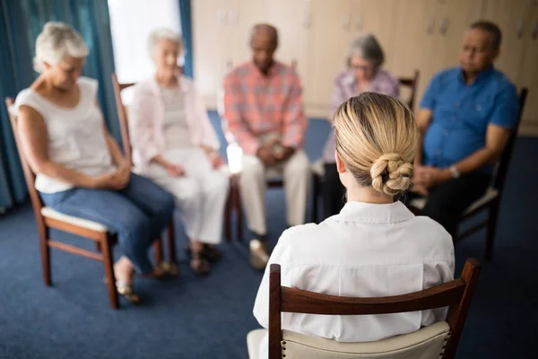 Женщина-врач медитирует с пожилыми людьми — стоковое фото