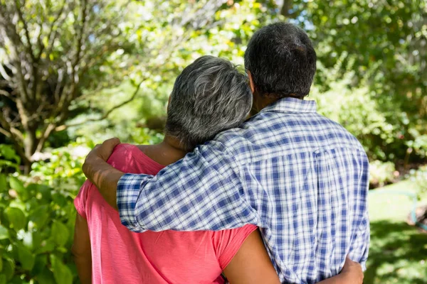 Casal sênior abraçando uns aos outros no jardim em um dia ensolarado — Fotografia de Stock