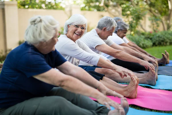 Mujer mayor con amigos haciendo ejercicio sobre esteras — Foto de Stock