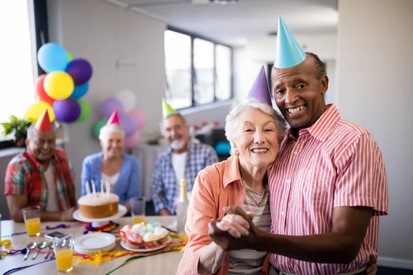 Couple âgé portant des chapeaux de fête debout à côté de la table — Photo