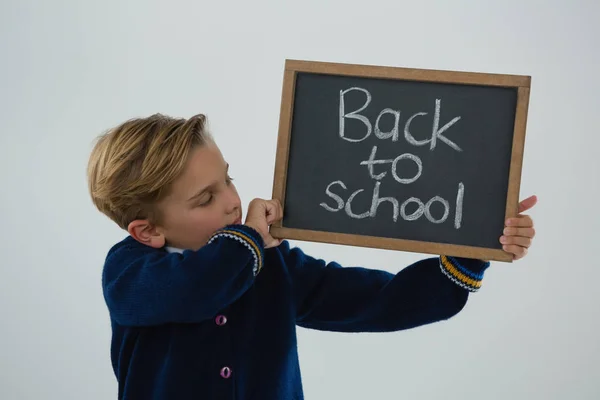 Schoolboy segurando ardósia com texto contra fundo branco — Fotografia de Stock