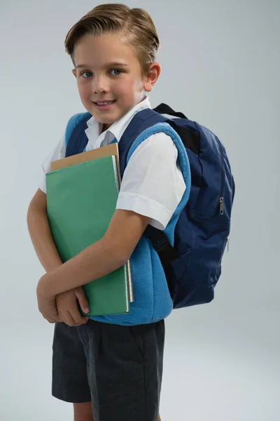 Porträt eines glücklichen Schuljungen mit Büchern vor weißem Hintergrund — Stockfoto