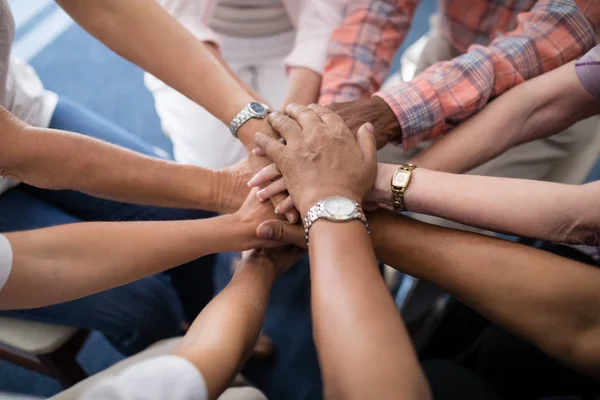 Senior mensen en vrouwelijke arts stapelen handen — Stockfoto