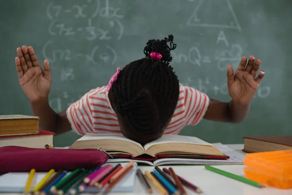 Schoolmeisje liggen op een open boeken in de klas — Stockfoto