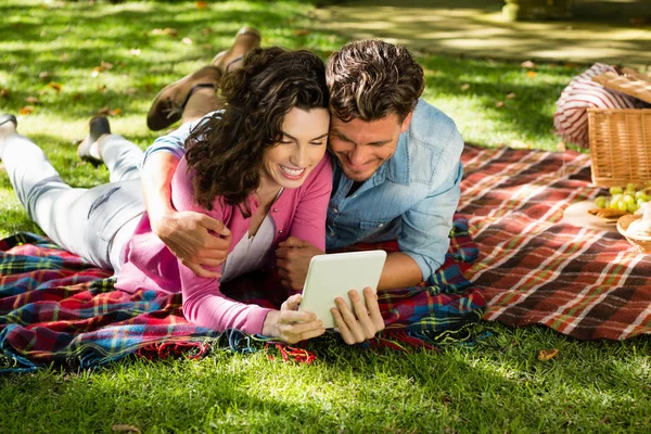 Paar liggend op picknick deken en het gebruik van digitale tablet — Stockfoto