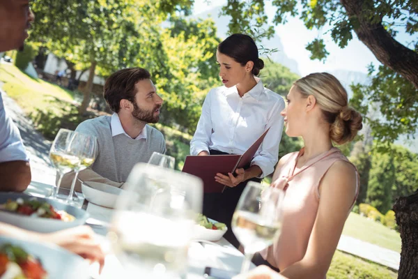 Garçonete discutindo o menu com o cliente — Fotografia de Stock