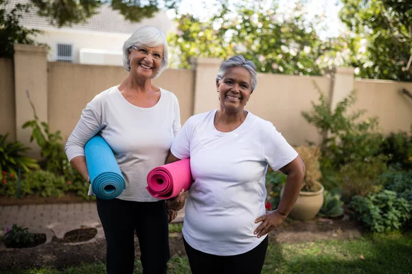 Amigos seniores carregando tapetes de exercício — Fotografia de Stock