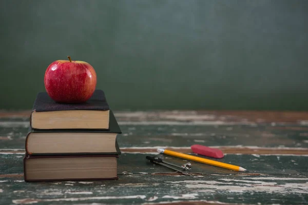 Manzana en la pila de libros con varios artículos de papelería — Foto de Stock