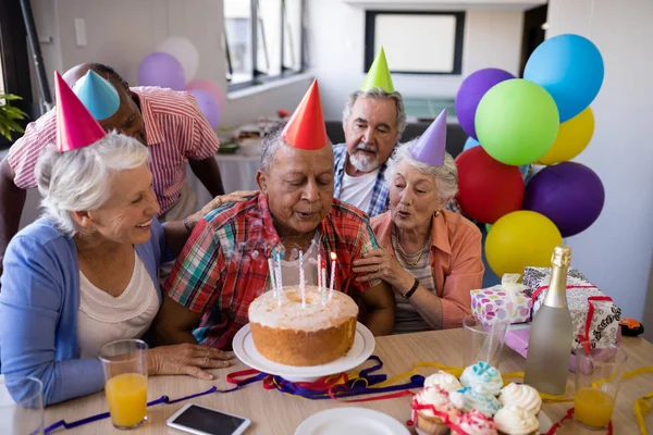 Homme âgé soufflant des bougies sur le gâteau d'anniversaire — Photo