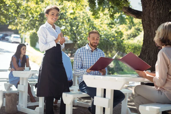 Leende servitris tar order från kund — Stockfoto