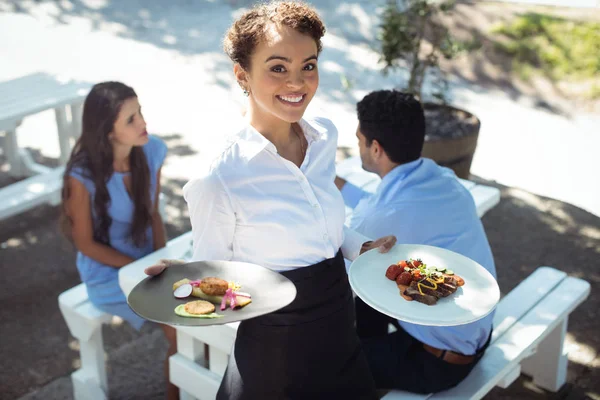 Camarera sonriente sosteniendo deliciosa comida —  Fotos de Stock