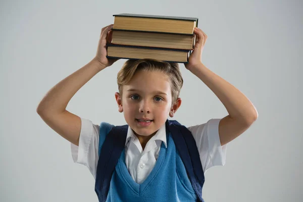 Schoolboy holding her book on her head — Stock Photo, Image