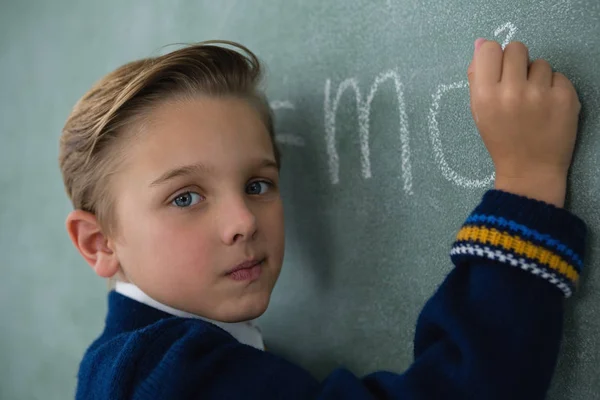 Schoolboy escrevendo fórmula matemática em quadro-negro — Fotografia de Stock