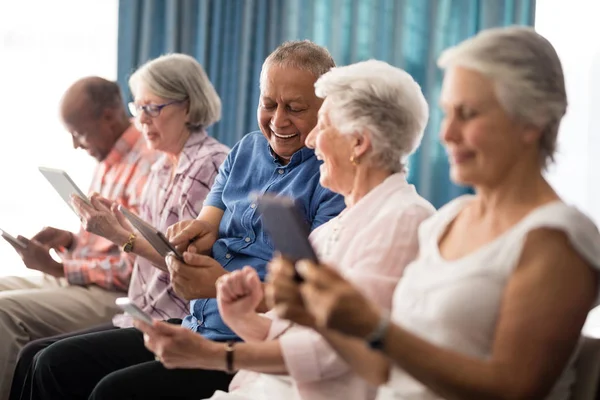 Senior mensen zitten op stoelen met behulp van tabletten — Stockfoto