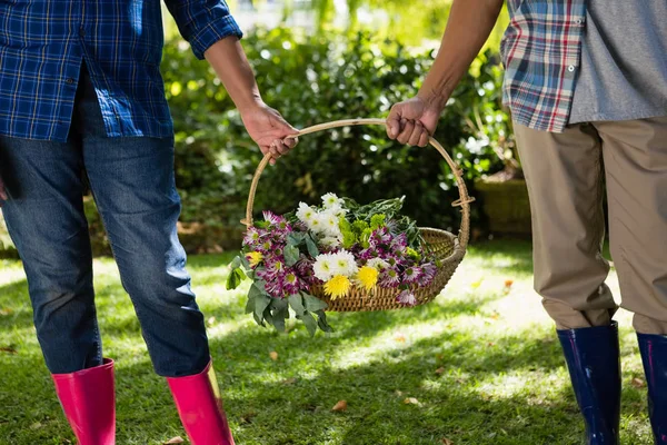 Coppia anziana che cammina in giardino con cesto di fiori — Foto Stock