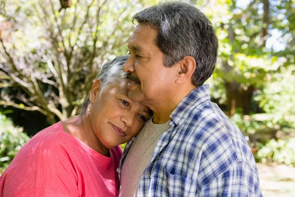 Äldre par omfamnar varandra i trädgården — Stockfoto