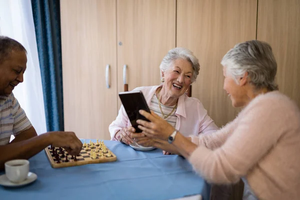 Friends playing chess and using technology — Stock Photo, Image