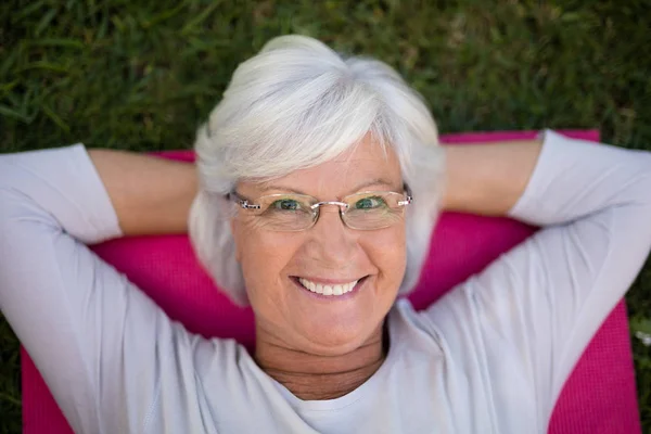 Senior woman lying on exercise mat — Stock Photo, Image