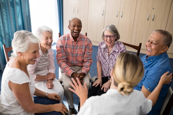 Anziani seduti con medico femminile su sedie — Foto Stock