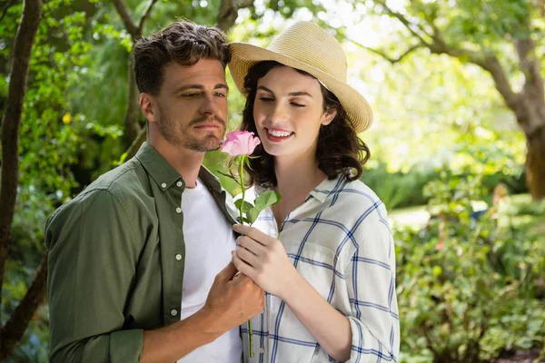 Smiling couple looking at flower in garden — Stock Photo, Image