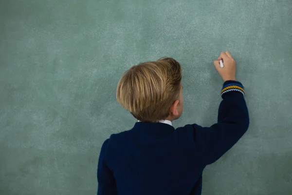 小学生用粉笔在黑板上写字 — 图库照片