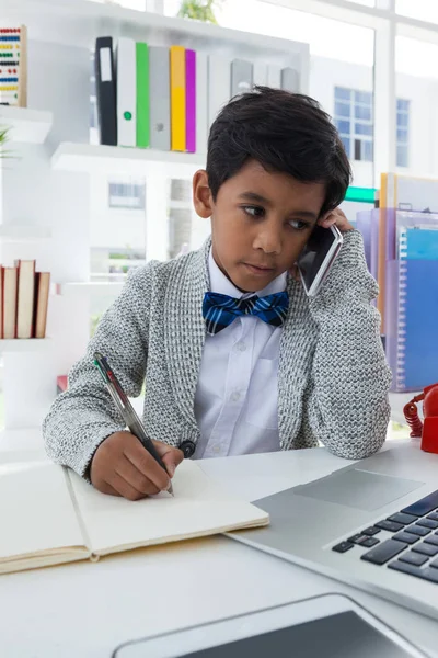 Businessman looking at laptop while talking on phone — Stock Photo, Image