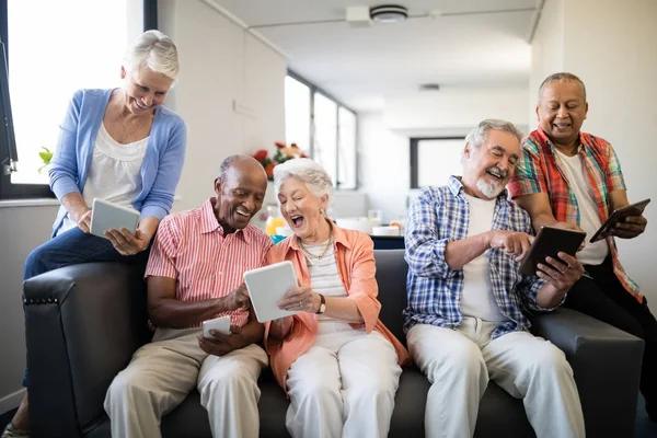 Amigos seniores mostrando tablet digital uns aos outros — Fotografia de Stock