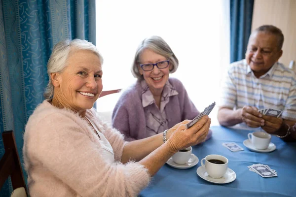 Старшие друзья играют в карты за чашкой кофе — стоковое фото