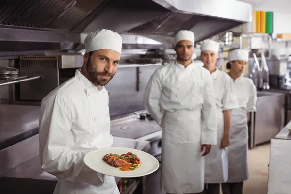 Chef segurando prato delicioso na cozinha — Fotografia de Stock