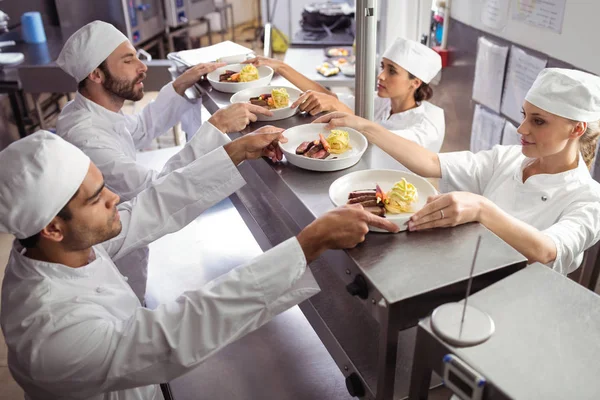 Chefs passando comida pronta para garçom — Fotografia de Stock
