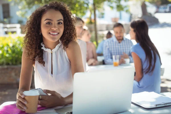 Hermosa mujer sosteniendo taza de café y teléfono móvil — Foto de Stock