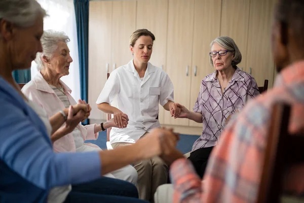 Arzt meditiert beim Händchenhalten mit Senioren — Stockfoto