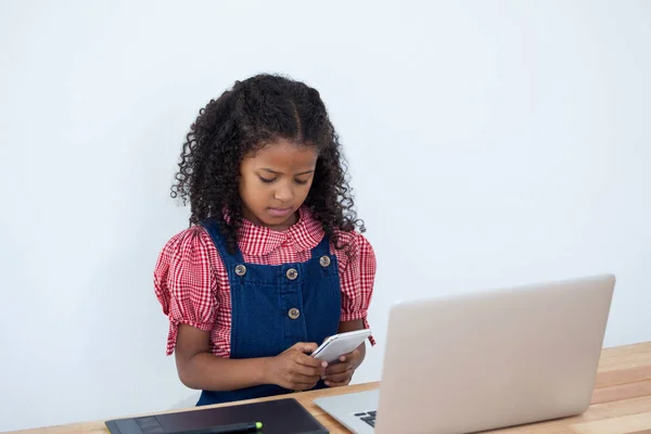 Zakenvrouw met behulp van telefoon zittend door laptop — Stockfoto