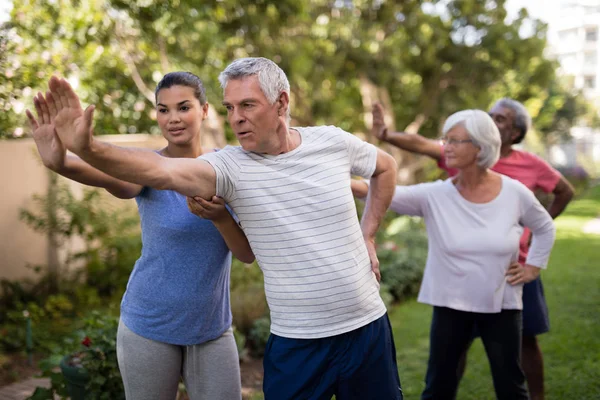 Treinador mostrando exercício de alongamento para pessoas idosas — Fotografia de Stock