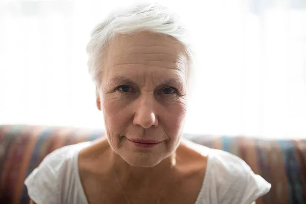 Woman sitting on sofa against window — Stock Photo, Image