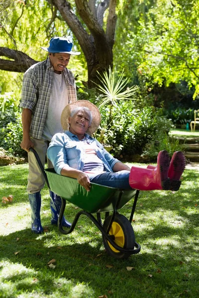 Starší muž dává žena jízda v trakaři — Stock fotografie