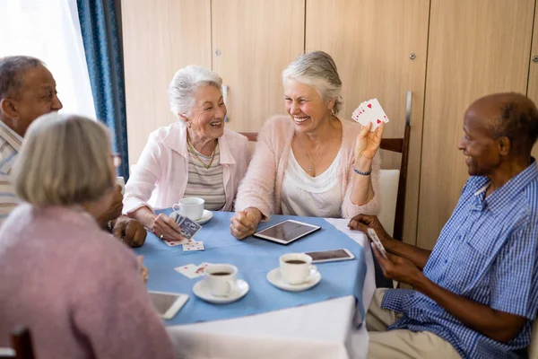 Senior mensen genieten van thee terwijl speelkaarten — Stockfoto