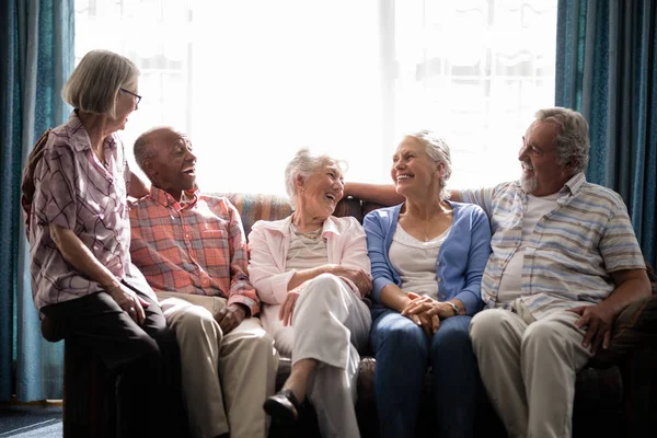 senior friends talking while sitting on couch