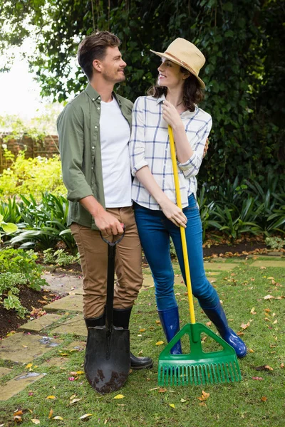 Пара, стоящая с садовыми грабли и лопаты — стоковое фото