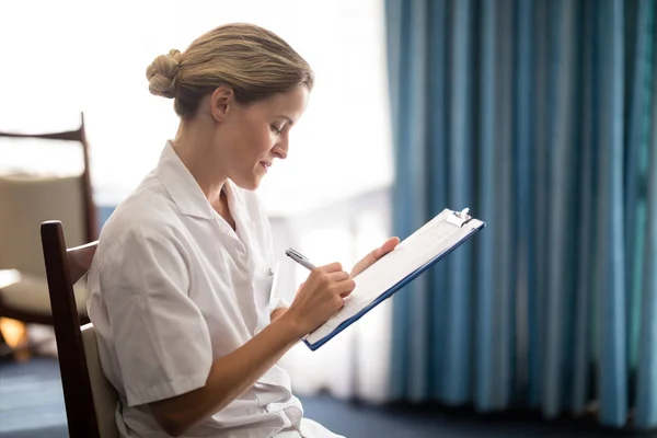 Female doctor writing on clipboard — Stock Photo, Image