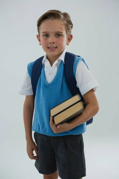 Beyaz arka plan üzerinde kitap tutan mutlu okul çocuğu portresi — Stok fotoğraf
