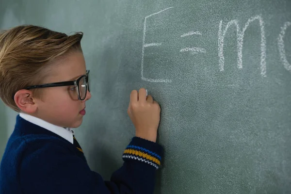 Colegial escribiendo fórmula de matemáticas en pizarra —  Fotos de Stock