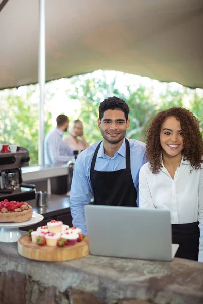 Manliga servitör och kvinnlig servitris med laptop — Stockfoto