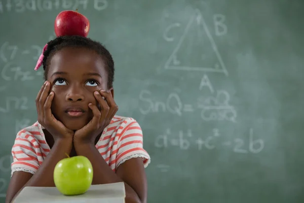 Schoolmeisje met rode appel op haar hoofd — Stockfoto