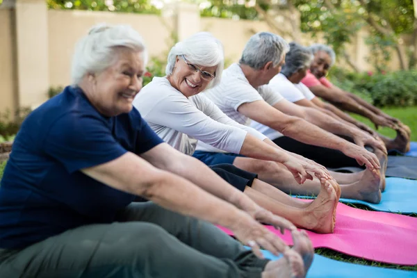 Senior femme avec des amis faire étirement — Photo