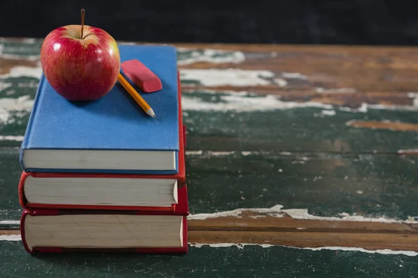 Apfel, Bleistift und Radiergummi auf Bücherstapel — Stockfoto