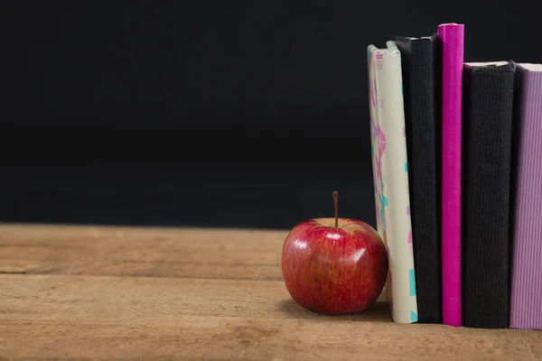 Apple en boeken over houten tafel — Stockfoto
